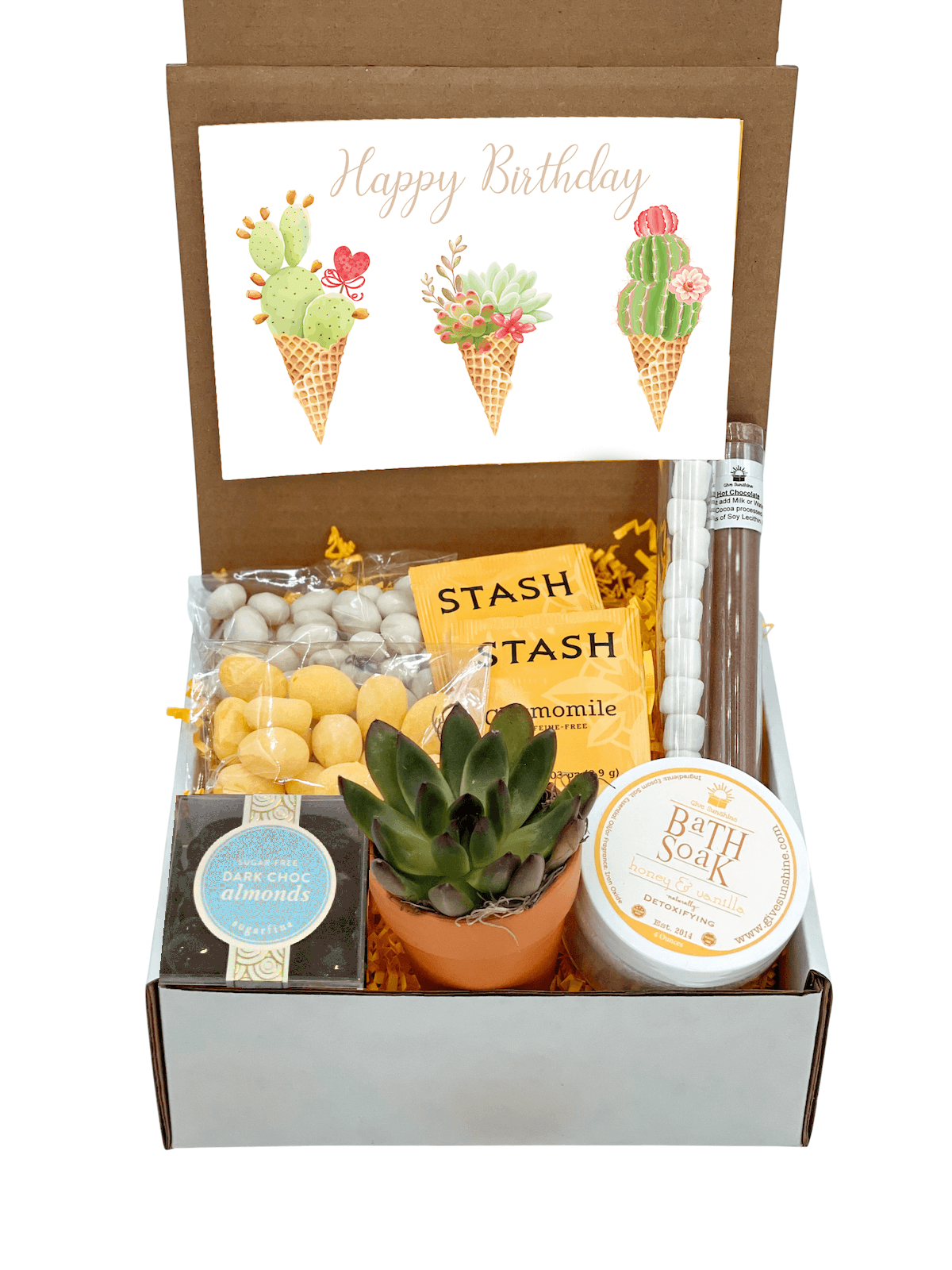 A gift box containing various items including a 'Sending you a little box of SUNSHINE' notecard, a 2.5-Inch Succulent in a Terra Cotta Pot, Honey & Vanilla Bath Soak, Dark Chocolate Covered Almonds, Hot Chocolate and Marshmallows, Lemon Drop Candies, Yogurt Covered Raisins, Chamomile Tea, and a 'Bit of Honey' candy.